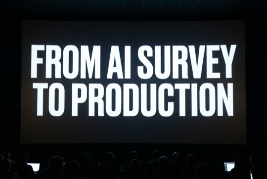 An AI-generated image of a talk title shown on a large, dimly lit conference screen above a silhouetted audience.