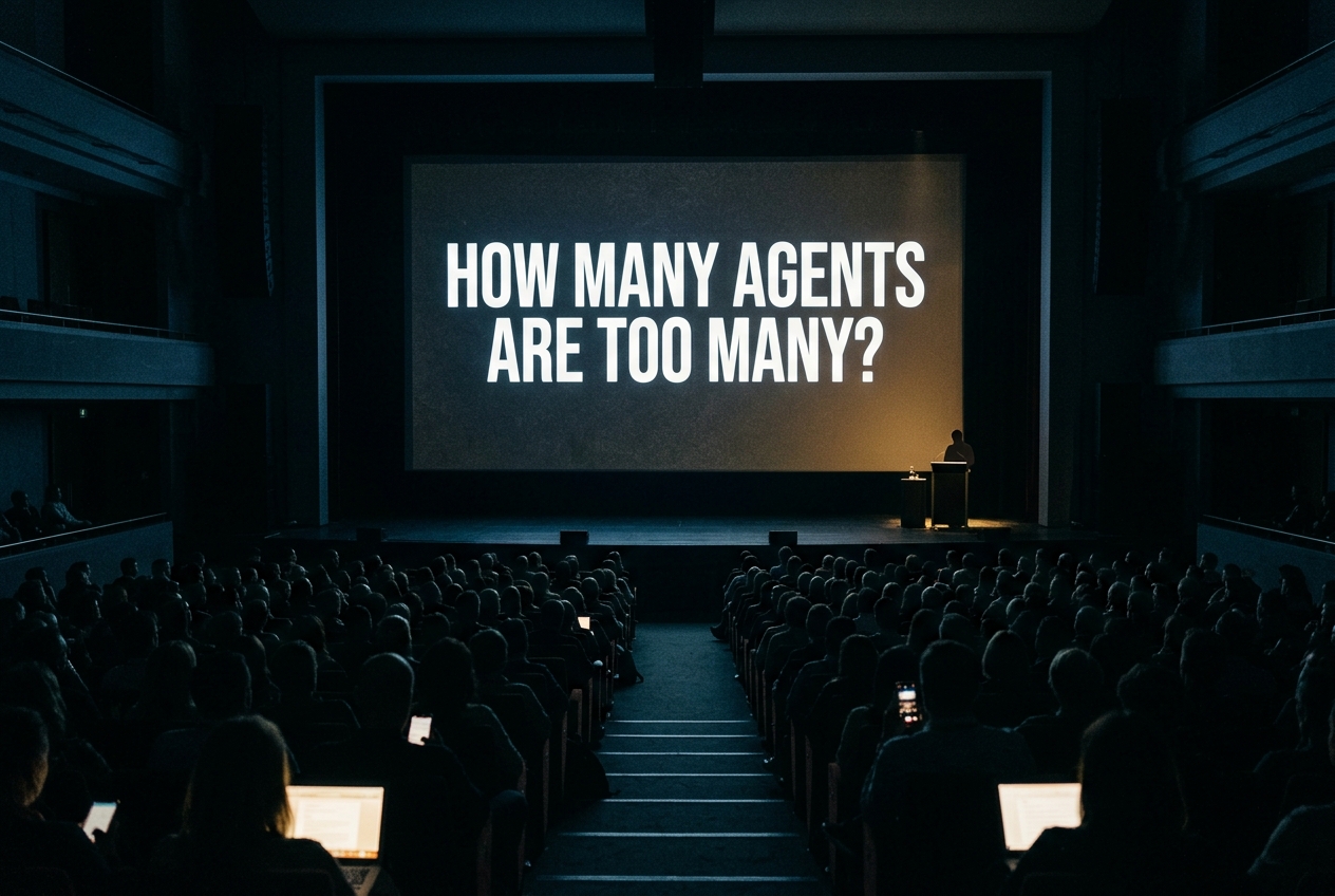 Reconstructed view from the back of a darkened auditorium toward a lit screen reading How Many Agents Are Too Many, the stage below nearly empty, audience silhouettes in the foreground.