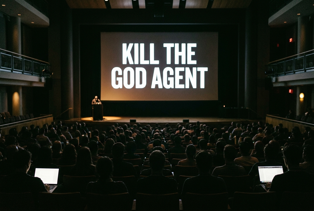 Reconstructed view from the back of a darkened auditorium toward a lit screen reading Kill the God Agent, the stage below nearly empty, audience silhouettes in the foreground.