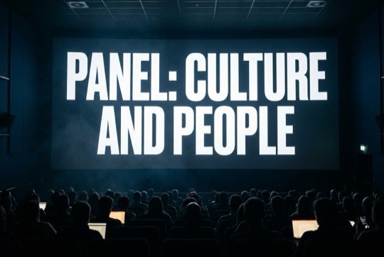 An AI-generated image of a talk title shown on a large, dimly lit conference screen above a silhouetted audience.